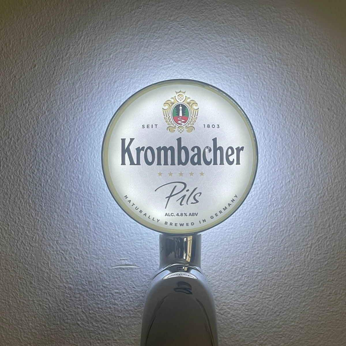 Krombacher badge lit up on a beer tap