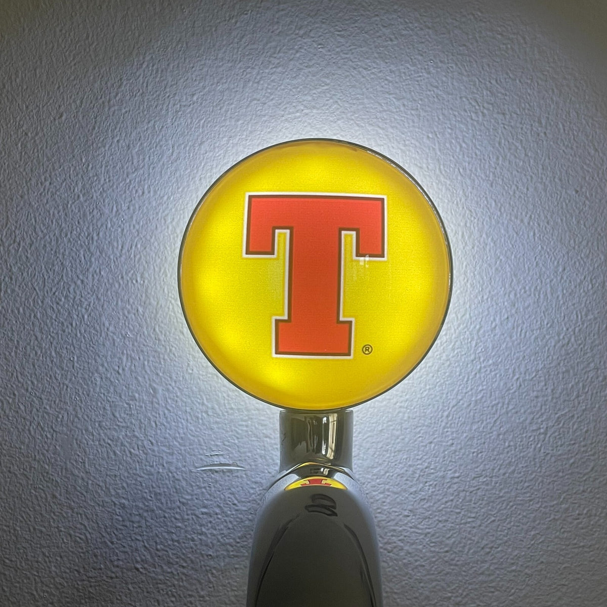 Tennent's Lager badge lit up on a beer tap
