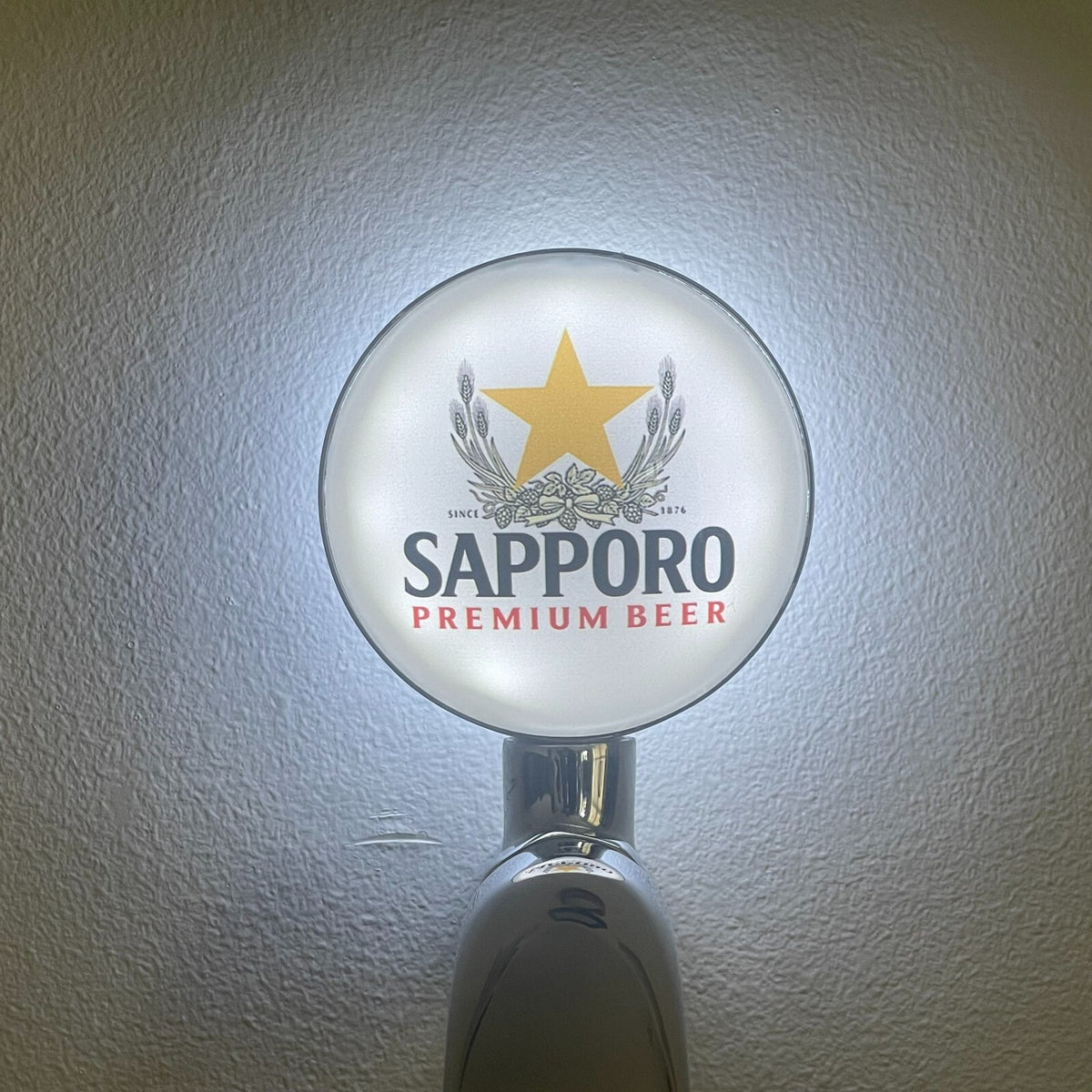 Sapporo badge lit up on a beer tap