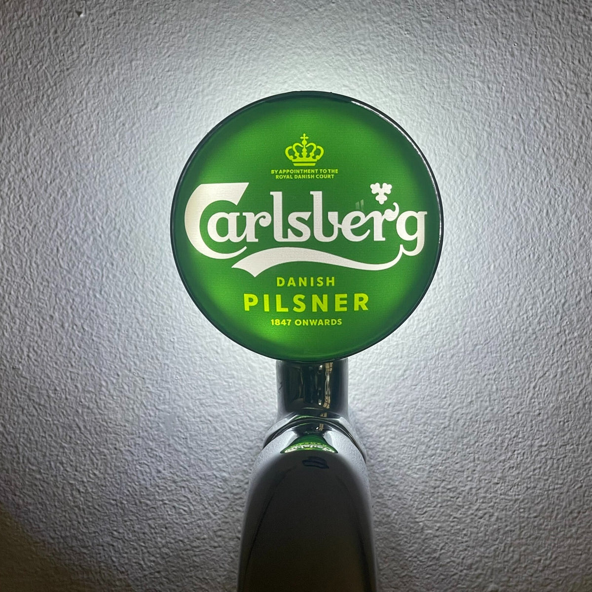 Carlsberg badge lit up on a beer tap