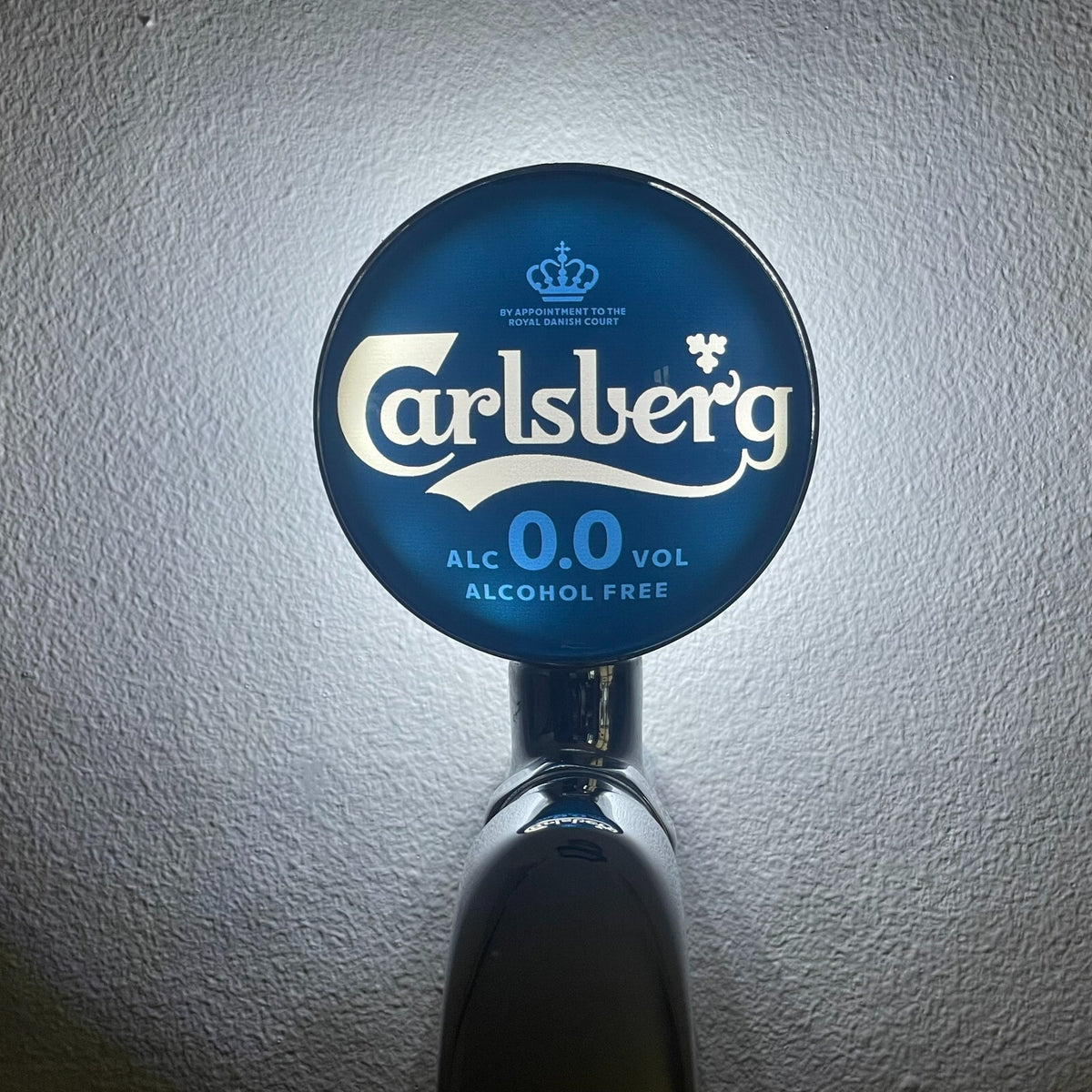 Carlsberg 0.0 badge lit up on a beer tap