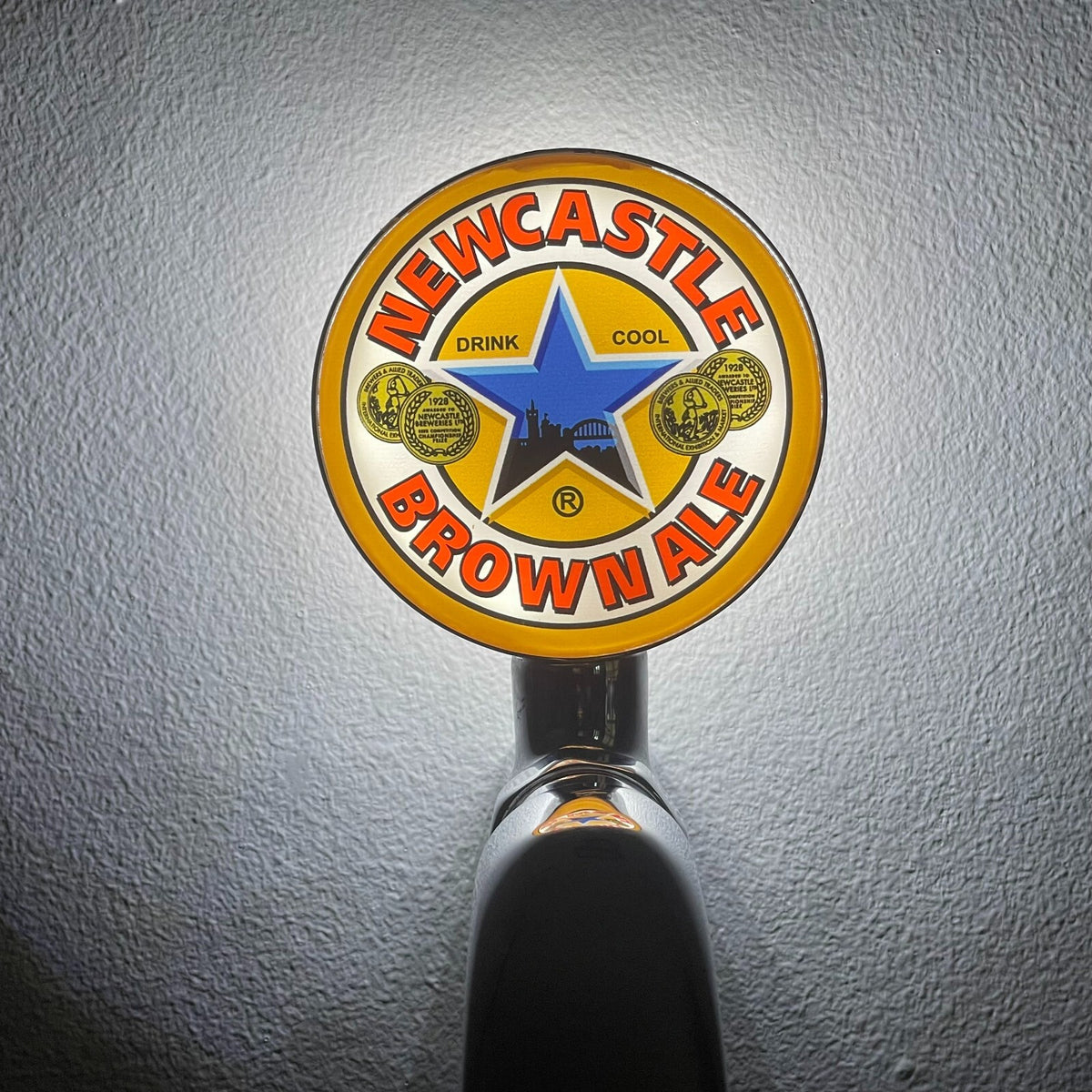 Newcastle Brown Ale badge lit up on a beer tap