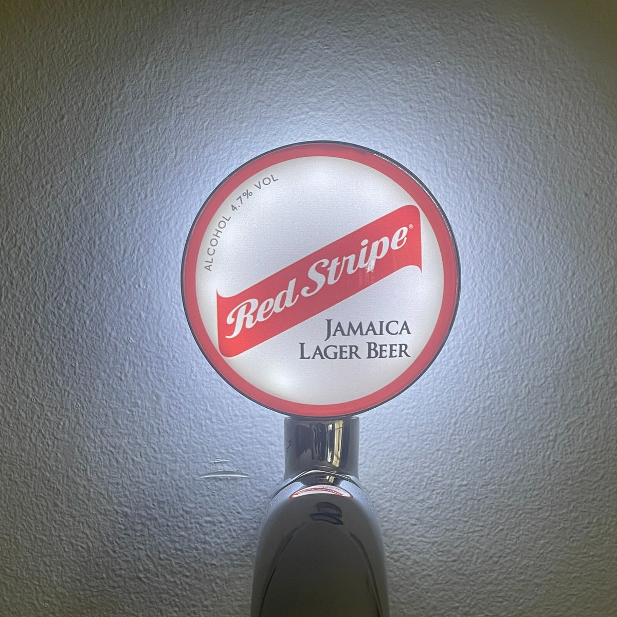 Red Stripe badge lit up on a beer tap